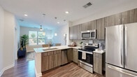 Located at 1055 Hatches Pond Ln in Cary, NC, this thoughtfully designed one-bedroom, one-bathroom residence offers a efficient and functional floor plan across a single level. The open-concept living and kitchen area creates a seamless flow, with the kitchen showcasing contemporary wood-toned cabinetry, quartz countertops, a subway tile backsplash, and a full suite of stainless steel appliances including a range, microwave, dishwasher, and refrigerator. Pendant lighting above the kitchen peninsula adds a stylish touch, while warm hardwood-style flooring runs throughout the main living areas. The living room is bright and welcoming, featuring a ceiling fan, a large window with outdoor views, and neutral wall tones that lend a clean, modern aesthetic. The bedroom is a comfortable retreat with plush carpet, a ceiling fan, and a generous window that invites natural light and outdoor views. The bathroom is elegantly finished with large-format tile flooring, a wood-toned vanity with a stone countertop, and a tiled walk-in shower. A dedicated walk-in closet is conveniently accessible from the bathroom. The entryway includes an in-unit washer and dryer, adding everyday convenience to this well-rounded Cary residence.