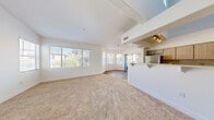 Located at 1350 W Horizon Ridge Pkwy in Henderson, NV, this two-bedroom, two-bathroom two-story residence offers a well-designed layout across two floors. The main level features a bright, open-concept living, dining, and kitchen area with soaring ceilings, large bay windows that invite abundant natural light, and plush carpeting throughout the living spaces. The kitchen is equipped with stainless steel appliances—including a gas range, microwave, and refrigerator—complemented by two-toned cabinetry, light quartz countertops, and wood-look flooring. A balcony extends from the main level, providing an outdoor retreat. Upstairs, a versatile loft area overlooks the lower level and leads to both bedrooms, each carpeted and featuring closets with built-in shelving. The spacious primary bedroom includes a walk-in closet. The two bathrooms are well-appointed; one features a soaking tub alongside a separate walk-in shower with a dark wood vanity and quartz countertop, while the second bath combines laundry facilities for added convenience. Five closets throughout the home offer generous storage. The clean, neutral palette and bright white walls create a light and airy ambiance throughout this thoughtfully laid-out Henderson residence.