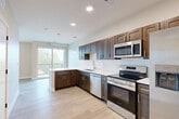 Located at 130 N 39th St in Omaha, Nebraska, this efficiently designed studio unit offers a thoughtfully utilized single-floor layout. The open-concept living and kitchen area is anchored by a stylish L-shaped kitchen featuring rich dark-brown shaker-style cabinetry, crisp white subway tile backsplash, light quartz countertops, and a full suite of stainless steel appliances including a range, microwave, dishwasher, and side-by-side refrigerator. A peninsula with pendant lighting provides additional prep space and serves as a natural divider between the kitchen and living area. Light wood-tone flooring runs throughout, lending warmth and visual continuity to the space. The living area is bathed in natural light from large windows and a sliding glass door that opens onto a private balcony, offering elevated views of the surrounding Omaha neighborhood. The bathroom features matching dark cabinetry with a white countertop vanity and light wood-look tile flooring, maintaining a cohesive design aesthetic. A dedicated closet provides practical storage. The overall ambiance is clean, modern, and bright, making this a functional and attractive urban living space.