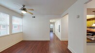 This single-floor, 2-bedroom, 2-bathroom residence offers a practical and comfortable layout with consistent design elements throughout. Rich, dark hardwood flooring flows seamlessly across the main living areas and bedrooms, lending warmth and visual continuity to the space.

The open living area is bright and airy, benefiting from natural light through slatted blinds and a ceiling fan that enhances airflow and comfort. A central hallway connects the main rooms efficiently, with recessed lighting guiding the way.

The kitchen features warm wood cabinetry, dark granite-style countertops, and stainless steel appliances including a range and microwave. Pendant lighting above the sink area adds a decorative touch, while bold accent walls provide a distinct character.

Both bathrooms are finished with dark tile flooring, wood vanities, and dark granite countertops. One bathroom includes a tub-shower combination with a large mirror and vanity lighting, while the second is equipped with accessibility features including grab bars, offering added functionality.

The bedrooms are generously sized with clean white walls, hardwood floors, ceiling fans, and closet storage. A dedicated in-unit laundry room houses a full-size side-by-side washer and dryer, adding everyday convenience to this well-designed residence.
