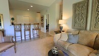 Located at 1802 Kellys Path in Reynoldsburg, Ohio, this single-floor home offers a thoughtfully designed open-concept layout that promotes a seamless flow between living and dining areas. The living room is warm and inviting, featuring plush carpeting, recessed lighting, and vaulted ceilings that lend a sense of spaciousness. Neutral wall tones and soft lighting create a calm, welcoming ambiance throughout the space. A breakfast bar with barstool seating connects the living area to the kitchen, making it ideal for casual dining and entertaining. Tile flooring in the kitchen area provides a practical contrast to the carpeted living space, clearly delineating the two zones. Doorways lead to additional rooms, suggesting a well-organized floor plan with comfortable separation between living and private spaces. Decorative wall accents and carefully placed lighting add character and a homey aesthetic. The overall design balances functionality with comfort, making this single-story Reynoldsburg home a practical and pleasant living environment.