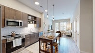 Located at 410 E 7th St in Frederick, MD, this thoughtfully designed one-bedroom, one-bathroom unit offers a efficient and modern single-floor layout. The open-concept kitchen and living area serves as the heart of the space, featuring rich dark-toned cabinetry, a white subway tile backsplash, stainless steel appliances including a refrigerator, electric range, built-in microwave, and dishwasher, as well as a kitchen island with seating. Stylish pendant lighting highlights the kitchen area, while light wood-style flooring runs throughout, adding warmth and continuity. The living area is bathed in natural light through large windows and a glass door that opens to the outdoors, creating an inviting, airy atmosphere. The bedroom is a comfortable retreat with plush carpeting, large windows with natural light, and neutral tones that promote a calm ambiance. The full bathroom features tile flooring, a vanity with dark cabinetry, and a tub-shower combination. Additional practical features include two closets and a dedicated in-unit laundry area, enhancing day-to-day convenience. The unit's clean, contemporary aesthetic and functional layout make it a well-appointed residence in the heart of Frederick.