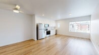 Located in Lacey, WA, this thoughtfully designed studio offers a clean, modern aesthetic with a bright, open-concept layout. Light hardwood flooring extends throughout the entire space, complementing the crisp white walls and recessed lighting that keep the interior feeling airy and well-lit.

The combined kitchen and living area forms the heart of the unit. The kitchen is outfitted with white shaker-style cabinetry, a full suite of stainless steel appliances — including a refrigerator, electric range, microwave, and dishwasher — and a single-basin sink. The open living area benefits from large windows fitted with horizontal blinds that frame views of the surrounding neighborhood and allow generous natural light to fill the room. A ceiling fan adds comfort and functionality.

The unit includes two bathrooms, each finished in white with light hardwood-style flooring, white vanity cabinetry, and bright vanity lighting. One bathroom features a shower/tub combination, while the other is positioned adjacent to a dedicated walk-in closet equipped with wire shelving. A stacked washer and dryer unit is conveniently located within this same area, adding practical in-unit laundry access. A dedicated entrance completes this efficiently organized, move-in ready space.