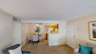 Located at 11171 W 17th Ave in Lakewood, Colorado, this single-floor residence offers a well-organized layout designed for comfortable everyday living. The living room serves as a welcoming central space, featuring a fireplace with a clean white mantle and large sliding glass doors that open to a private patio, filling the room with natural light and providing views of the surrounding greenery. Soft carpeting throughout the living areas contributes to a warm, relaxed ambiance.

The living and dining areas flow naturally into one another, with the dining space accommodating a full table and sitting beneath a ceiling fan. A half-wall peninsula connects the dining area to the galley-style kitchen, which is efficiently arranged with warm wood cabinetry lining both sides, light countertops, a double sink, and full suite of white appliances including a refrigerator, range, microwave, and dishwasher. Light wood-style flooring runs through the kitchen, contrasting with the carpeted living spaces.

The bedroom is generously proportioned, featuring plush carpet, a large window with outdoor views, and access to a walk-in closet with built-in shelving. The bathroom includes a wide dual-sink vanity with a large mirror and overhead lighting, providing ample counter space and functionality.