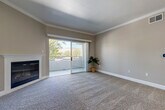 This 2-bedroom, 2-bathroom residence offers a thoughtfully designed single-floor layout that maximizes both comfort and functionality. The open-concept living and kitchen area serves as the heart of the home, featuring plush carpeting in the living room alongside a fireplace and sliding glass doors that open to a private balcony with outdoor views. Crown molding adds a refined touch throughout the common areas.

The kitchen is well-equipped with stainless steel appliances—including a French door refrigerator, electric range, and microwave—complemented by taupe cabinetry, white countertops, a peninsula with a sink, and light wood-look vinyl flooring. Recessed lighting illuminates the space effectively.

The primary bedroom is generously sized, featuring carpet flooring, neutral wall tones, and natural light from multiple windows. The second bedroom offers a comparable layout with dual windows and soft carpet. Both bathrooms are finished consistently, with taupe vanity cabinetry, white countertops, and a tub-shower combination backed by clean white tile surround.

A hallway connects the rooms, maintaining a practical flow throughout. The unit's neutral color palette—warm greiges, white trim, and natural-toned flooring—creates a cohesive, move-in-ready aesthetic suited for a variety of décor styles.