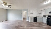 Located at 400 Rosewood Ave in Boerne, TX, this single-story 2-bedroom, 1-bathroom home offers a thoughtfully updated interior with a clean, modern aesthetic. The open-concept kitchen and living area serves as the heart of the home, featuring durable wood-look flooring, soft blue-gray walls, and a textured ceiling. The kitchen is well-appointed with sage-toned shaker cabinets, granite countertops, a striking floor-to-ceiling marble-style tile backsplash, and black appliances including a range, dishwasher, and refrigerator. Floating shelves add a contemporary touch above the counter space.

Both bedrooms are carpeted and equipped with ceiling fans and windows that invite natural light. The primary bedroom is a comfortable size with access to a closet, while the second bedroom also features a window with outdoor views of surrounding trees. A hallway connects the living spaces to the bedrooms and bathroom.

The bathroom is finished with a granite-topped vanity, wood-look flooring, and a walk-in shower enclosed by sliding glass doors with large-format gray tile surround. Throughout the home, consistent finishes and neutral tones create a cohesive and move-in-ready feel.