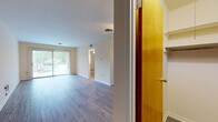 This single-floor residence offers a well-organized layout that balances open communal areas with private living spaces. The main living and dining area is spacious and bright, featuring durable hardwood-style flooring in a neutral gray tone that runs throughout the common areas, creating a cohesive and modern aesthetic. A sliding glass door fills the space with natural light and provides direct access to an outdoor balcony, offering pleasant views of surrounding greenery.

The kitchen is positioned adjacent to the main living area and features rich, dark-stained wood cabinetry paired with granite-patterned countertops, a double stainless steel sink with a modern pull-down faucet, and hardwood-style flooring that complements the rest of the unit. Ceiling fans are installed in both the living area and bedroom, enhancing comfort throughout.

The bedroom is generously sized, finished with plush wall-to-wall carpet, and includes a large sliding-door closet with dual hanging rods and built-in shelving, offering ample storage. A window allows for natural light and outdoor views. The bathroom features a full tub-and-shower combination with white tile surround, a single-sink vanity with white cabinetry, and hardwood-style flooring. Overall, the space presents a clean, functional, and comfortable environment.
