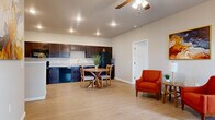 This single-floor residence offers a thoughtfully laid-out floor plan encompassing two bedrooms and three bathrooms. The entry hallway, finished with light wood-style flooring and recessed lighting, leads seamlessly into the open-concept living and kitchen area. The kitchen is equipped with rich dark-stained cabinetry, light granite-style countertops, black appliances including a refrigerator, range, dishwasher, and microwave, as well as a double-basin sink. A ceiling fan with lighting anchors the combined living and dining space, which is spacious enough to accommodate a dining set and lounge seating. The primary bedroom is a generously sized retreat featuring plush carpet, a ceiling fan, a large window that invites natural light, and a built-in closet with wire shelving. The second bedroom is similarly carpeted and includes its own closet. The three bathrooms are well-appointed, featuring dark wood vanities with granite-style countertops, light wood-style flooring, and tub-shower combinations. Neutral warm-toned walls and clean white trim are consistent throughout, contributing to a cohesive and move-in-ready aesthetic across the entire residence.