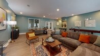 Located at 1334 Xanadu St in Aurora, Colorado, this single-floor community amenity space is designed to foster gathering and relaxation in a thoughtfully curated environment. The open-concept layout is anchored by a spacious lounge area finished with warm wood-tone flooring and signature teal-blue accent walls that lend the space a cohesive, modern character throughout.

The lounge area is generously appointed with a large sectional sofa, patterned area rug, and accent chairs, all centered around a glass-top coffee table. A wall-mounted flat-screen TV, curated artwork, and decorative lighting complete the media and social zone. A striking live-edge communal table with bench seating serves as a natural gathering point, complemented by additional candleholder décor for ambiance.

A shuffleboard table adds a recreational element to the space, enhancing its communal appeal. The fully equipped kitchen features gray shaker-style cabinetry, white quartz countertops, a classic subway tile backsplash, and stainless steel appliances including a full-size refrigerator and microwave. A peninsula counter with bar stools provides casual seating and a seamless connection between the kitchen and lounge. Recessed lighting throughout ensures a bright, welcoming atmosphere ideal for community events and everyday use.