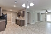 This single-story residence in Canton, Georgia presents a well-organized layout with a neutral color palette and a mix of flooring materials throughout. The hallway connecting the main living areas features light wood-look luxury vinyl plank flooring, crown molding, and flush-mount lighting, establishing a clean and polished entry into the home.

The galley-style kitchen is a functional highlight, featuring dark espresso cabinetry extending to the ceiling on both sides, granite countertops, a tile backsplash, and black appliances including a range, refrigerator, and dishwasher. A walk-in pantry with wire shelving is accessible directly from the kitchen, providing ample storage.

The bedrooms are carpeted and include ceiling fans with lighting. Each room benefits from natural light through blinded windows, with outdoor views of the surrounding neighborhood. One bedroom features a walk-in closet with wire shelving systems and connects to a private bathroom.

The bathrooms are finished with dark vanity cabinetry, granite countertops, and wood-look LVP flooring. The primary bath includes both a separate glass-enclosed shower and a tiled soaking tub, while a secondary bath offers a tub-shower combination with brushed nickel fixtures throughout.