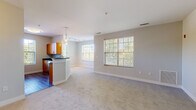 Located at 32 Seven Springs Lane in Burlington, MA, this single-floor residence offers a thoughtfully designed open-concept layout that seamlessly connects the kitchen and living areas. The living space is finished with plush neutral carpeting and framed by large windows fitted with slatted blinds, allowing generous natural light to filter in while offering views of the surrounding greenery.

The kitchen is well-equipped with warm-toned wood cabinetry, dark granite countertops, a glass tile backsplash, and a full suite of stainless steel appliances including a refrigerator, range, and over-the-range microwave. Pendant lighting above the peninsula adds a functional and stylish focal point to the space, while hardwood flooring grounds the cooking area.

The bedrooms are generously proportioned, each carpeted and featuring windows with outdoor views. The primary bedroom includes a walk-in closet with built-in shelving and a dedicated en-suite bathroom. Both bathrooms are finished with large-format tile flooring, warm wood vanities, dark granite countertops, illuminated mirrors, and tub-shower combinations, creating a clean and consistent aesthetic throughout the residence.