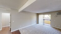 This single-level, one-bedroom, one-bathroom unit offers a thoughtfully arranged floor plan that maximizes its compact footprint. The combined kitchen and living area forms the heart of the space, where warm hardwood-style flooring transitions into plush carpet in the living zone. The kitchen is outfitted with white cabinetry, a stainless steel double-basin sink set into a light stone countertop, a stainless steel range, and an overhead range hood — all lending a clean, functional aesthetic. A ceiling fan with light fixture provides overhead comfort in the adjoining area. The living room is bright and open, with a sliding glass door dressed in vertical blinds that leads to a private balcony with outdoor views, allowing natural light to fill the room. A wall-mounted HVAC unit provides additional climate control. The bedroom is a comfortable, well-proportioned room with plush carpet, a window with natural light, and direct access to a generously sized walk-in closet outfitted with multiple shelving units and a hanging rod for ample storage. The full bathroom includes a combined tub and shower with clean white surround and brushed nickel fixtures. Textured ceilings are found throughout, adding a consistent design element across the unit.