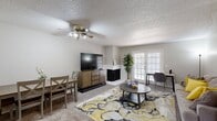 Located at 12700 Indian Creek Blvd in Oklahoma City, Oklahoma, this two-bedroom, two-bathroom single-floor home offers a well-organized layout designed for comfortable everyday living. The living room serves as the central gathering space, featuring a white brick corner fireplace, plush carpeting, a ceiling fan, and a set of French doors that invite natural light and provide outdoor access. The kitchen is equipped with rich dark wood cabinetry, light countertops, black appliances including a range, dishwasher, and refrigerator, and wood-look flooring that adds warmth to the space. A window above the sink brings in additional natural light. The primary bedroom is a generously sized retreat with carpet flooring, a large window overlooking the outdoors, and a dedicated closet with built-in shelving. Both bathrooms are well-appointed, featuring white vanities with light countertops, tub-shower combinations with tiled surrounds, and wood-look flooring. The second bathroom includes a mirrored medicine cabinet with shutter-style detailing. Each bedroom benefits from its own closet, and hallways connect the rooms efficiently throughout the home. The textured ceilings present throughout add a consistent architectural character to the space.