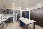 Located at 3401 E Washington Ave in Madison, WI, this well-designed one-bedroom, one-bathroom unit offers a functional and modern living experience. The open-concept layout seamlessly connects the kitchen, dining, and living areas, creating a spacious and cohesive main living space. The kitchen is a standout feature, boasting rich dark cabinetry, a white subway tile backsplash, stainless steel appliances including a refrigerator, electric range, microwave, and dishwasher, and a granite-topped island with pendant lighting overhead — ideal for both meal prep and casual dining. Light wood-tone flooring runs throughout the main living areas, complementing the contemporary aesthetic. The living area includes sliding glass door access to a private balcony with outdoor views. The bedroom features plush carpeting, a ceiling fan, a large window that brings in natural light, and direct access to a spacious walk-in closet with wire shelving. The bathroom is finished with a granite vanity countertop, dark cabinetry, and a clean, neutral color palette. In-unit laundry adds everyday convenience. Recessed lighting and dark-finished interior doors complete the modern, polished look throughout.