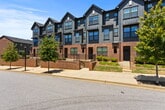 Located at Northside Townes in Spartanburg, SC, this three-story townhome offers 1,530 square feet of living space across three floors, featuring 3 bedrooms and 3 full bathrooms. The entry-level floor encompasses 250 square feet and provides access to the staircase leading to the main living areas. The primary living level spans 690 square feet and showcases an open-concept layout combining the kitchen, dining room, and living room. The kitchen is appointed with rich dark-wood cabinetry, granite countertops, a large kitchen island with an integrated sink, stainless steel appliances including a refrigerator with ice maker, microwave, and range. The dining area features a stylish pendant chandelier and multiple windows offering neighborhood views. The living room includes durable light-toned LVP flooring and a ceiling fan, with a glass door leading to an outdoor balcony. The upper floor covers 590 square feet and houses the bedrooms, including a 150 sq ft primary bedroom with an en-suite bathroom featuring granite vanity, and a walk-in closet with built-in wire shelving. Additional bedrooms also include ceiling fans and LVP flooring. Each bathroom is outfitted with a tub-shower combination. A dedicated laundry room with Samsung washer/dryer and overhead wire shelving adds everyday convenience.