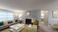 Located at 1025 Avent Hill in Raleigh, NC, this single-floor residence offers a well-organized layout with a thoughtfully designed interior finished in neutral gray tones throughout. The living room serves as the central gathering space, highlighted by a classic fireplace with a white mantle, plush carpeting, and windows that allow natural light to filter in. A patio door provides direct access to the outdoors, enhancing the sense of openness. The kitchen is equipped with crisp white cabinetry, granite-style countertops, and black appliances including a range and over-the-range microwave, combining functionality with a clean, modern aesthetic. The bedroom is a comfortable retreat featuring soft carpeting, a window with natural light, and ample space for furnishings. The full bathroom is well-appointed with a granite-topped vanity, white cabinetry, a tub/shower combination, and wood-look flooring that adds a contemporary touch. A dedicated laundry area with a full-size washer and dryer, complete with built-in wire shelving above, adds a high level of everyday convenience. Throughout the home, consistent finishes and soft tones create a cohesive and comfortable living environment.