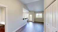 Located at 5715 Red Leaf Dr S, Unit 301 in Salem, Oregon, this one-bedroom, one-bathroom residence offers a thoughtfully arranged single-floor layout with a clean, neutral aesthetic throughout. The kitchen is well-appointed with dark espresso-toned cabinetry, stainless steel appliances including a refrigerator, range, and microwave, light hardwood-style flooring, and a built-in pantry. A pendant chandelier and natural light from a window create a warm dining ambiance in the adjacent area. The living and main areas continue the light hardwood-style flooring, offering an open and airy feel enhanced by vaulted ceiling details visible in portions of the space. The bedroom is generously sized, featuring plush carpeting, dual windows that invite natural light and outdoor views of surrounding greenery, a ceiling fan with light fixture, and a double-door closet for ample storage. The bathroom is finished with rich dark wood cabinetry, a white countertop vanity, a large mirror, and a full tub/shower combination, all set on light hardwood-style flooring. The overall design balances modern fixtures with warm tones, creating a comfortable and functional living environment.