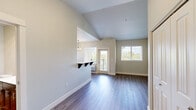 Located at 5715 Red Leaf Dr S, Unit 301 in Salem, Oregon, this one-bedroom, one-bathroom residence offers a thoughtfully arranged single-floor layout with a clean, neutral aesthetic throughout. The kitchen is well-appointed with dark espresso-toned cabinetry, stainless steel appliances including a refrigerator, range, and microwave, light hardwood-style flooring, and a built-in pantry. A pendant chandelier and natural light from a window create a warm dining ambiance in the adjacent area. The living and main areas continue the light hardwood-style flooring, offering an open and airy feel enhanced by vaulted ceiling details visible in portions of the space. The bedroom is generously sized, featuring plush carpeting, dual windows that invite natural light and outdoor views of surrounding greenery, a ceiling fan with light fixture, and a double-door closet for ample storage. The bathroom is finished with rich dark wood cabinetry, a white countertop vanity, a large mirror, and a full tub/shower combination, all set on light hardwood-style flooring. The overall design balances modern fixtures with warm tones, creating a comfortable and functional living environment.