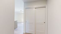 Located at 7219 Sharon Ave in Niagara Falls, Ontario, this thoughtfully designed one-bedroom, two-bathroom unit offers a clean, contemporary aesthetic throughout its efficiently laid-out single floor. Light hardwood flooring runs consistently through the main living areas, creating a warm and cohesive feel.

The kitchen is a standout feature, showcasing a large island with a light wood base and white quartz countertop, complemented by matching upper cabinetry and a subway tile backsplash. Stainless steel appliances, including a refrigerator, stove, and built-in microwave, add a polished, functional touch. The open-concept layout allows the kitchen to flow naturally into the living area, making the space feel open and connected.

The bedroom is bright and inviting, featuring a large window overlooking lush greenery, a double-door closet offering generous storage, and the same warm hardwood flooring found throughout the unit. The neutral wall tones contribute to a calm and restful atmosphere.

Both bathrooms are finished with modern fixtures. One bathroom features a stylish vanity with light wood cabinetry, a white quartz countertop, and large-format tile flooring, reflecting the same design language carried throughout the unit. A hallway connects all areas of the floor plan seamlessly. Overall, this unit presents a fresh, modern living environment with consistent, quality finishes.