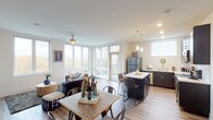 This single-floor residence is designed with a contemporary open-concept layout that seamlessly connects the living, dining, and kitchen areas. The living space is bright and airy, benefiting from a generous arrangement of floor-to-ceiling windows and a glass-panel balcony door that floods the interior with natural light and offers views of surrounding greenery. A ceiling fan overhead adds both function and style to the space.

The kitchen is well-appointed with dark espresso cabinetry, light quartz countertops, a white subway tile backsplash, and a full suite of stainless steel appliances. A central island with seating provides additional prep space and casual dining options, while pendant lighting adds a refined touch. Light wood-style flooring flows throughout the common areas, lending warmth and continuity.

Two comfortably sized bedrooms each feature ceiling fans, large windows with outdoor views, and neutral finishes. The bathrooms are clean and functional, with one featuring a full tub-shower combination, white cabinetry, and light stone countertops. Wood-look tile flooring carries through the bathrooms, maintaining a cohesive aesthetic throughout the residence.