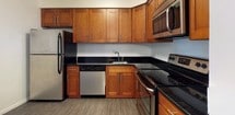 Located at 1800 Kuser Rd in Trenton, NJ, this single-floor residence offers a clean, neutral aesthetic throughout. The spacious living area is finished with plush carpeting and bathed in natural light from large windows fitted with blinds, creating a bright and welcoming atmosphere. A wall-mounted HVAC unit ensures year-round comfort. The living space flows openly into a separate dining area, accented by an elegant chandelier overhead, providing a defined yet connected layout. The kitchen is a functional standout, featuring rich warm-toned cabinetry, dark granite countertops, and a full suite of stainless steel appliances including a refrigerator, dishwasher, electric range, and built-in microwave, all set atop durable wood-look tile flooring. The bedroom is generously proportioned, with soft carpeting and two separate doorways leading to a dedicated closet and an adjoining room, offering excellent storage and flexibility. The bathroom is tastefully finished with crisp white subway tile accented by horizontal bands of darker tile, a soaking tub with a showerhead, chrome fixtures, and grey tile flooring, lending a clean, modern feel. Throughout the residence, neutral wall tones and consistent finishes create a cohesive and move-in ready environment.
