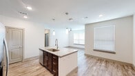 Located in Tomball, TX, this single-story, 3-bedroom, 2-bathroom home offers a well-designed open-concept layout that seamlessly connects the kitchen, dining, and living areas. The kitchen serves as the centerpiece of the home, boasting a large granite-topped island with an undermount sink, pendant lighting, rich dark-stained cabinetry, a white subway tile backsplash, and a full suite of stainless steel appliances including a French door refrigerator, electric range, and microwave. Wood-look plank flooring extends throughout the main living areas, adding warmth and continuity.

The primary bedroom is a generously sized retreat with a ceiling fan and access to a well-appointed en-suite bathroom featuring a dual-sink granite vanity with dark cabinetry, a glass-enclosed walk-in tile shower, and wood-look flooring. The secondary bedrooms are carpeted, each equipped with ceiling fans and windows fitted with blinds for natural light and privacy. The second bathroom offers a tiled soaking tub and shower combo with a granite vanity.

Additional highlights include a dedicated laundry room with full-size washer and dryer, two closets for storage, and a hallway connecting all rooms efficiently. The bright, neutral palette throughout lends the home a clean, modern aesthetic.