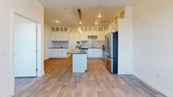 Located at 9465 W Post Rd in Las Vegas, NV, this well-appointed one-bedroom, one-bathroom unit offers a thoughtfully designed layout across a single floor. Wood-look plank flooring runs throughout, lending a warm, cohesive aesthetic to the space.

The open-concept kitchen, dining, and living area serves as the heart of the unit. The kitchen is outfitted with crisp white cabinetry extending to the ceiling — including glass-front upper cabinets and a built-in wine rack — complemented by dark quartz countertops and a classic subway tile backsplash. A central island provides additional prep and seating space, while pendant lighting adds a modern touch. Stainless steel appliances, including a gas range, microwave, and French door refrigerator, complete the kitchen. The adjacent living and dining area benefits from a large window that invites natural light and offers views of the surrounding cityscape.

A hallway connects the bedroom and bathroom, with a sliding-door closet providing convenient storage. The spacious bedroom features two large windows with urban views. The full bathroom is elegantly finished with a white vanity, quartz countertop, backlit mirror, and a tiled shower-tub combination. A dedicated laundry room houses a full-size washer and dryer, along with an additional utility area, rounding out this efficiently designed residence.