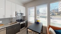 Located at 1606 Abbey Pl in Charlotte, NC, this single-floor unit offers a well-organized layout with a cohesive contemporary design. The kitchen is a standout feature, equipped with stainless steel appliances including a refrigerator, range, microwave, and dishwasher. White gloss upper cabinetry contrasts with darker lower cabinets, while granite countertops and a textured tile backsplash add visual interest. A dining area sits adjacent to the kitchen, positioned beside large windows fitted with horizontal blinds that allow ample natural light and views of the surrounding area.

The living room continues the light-filled theme, with a ceiling fan overhead and a window offering additional outdoor views. Clean white walls and light-toned flooring run throughout the space, creating a bright and airy atmosphere.

The bedroom is a calm retreat featuring high, angled walls that lend a sense of vertical space. Light hardwood-style flooring, neutral walls, and a ceiling fan contribute to a restful environment, with room for décor and furnishings.

The bathroom maintains the unit's clean aesthetic, featuring light tile flooring, granite countertops, and white walls, delivering a functional and polished finish throughout.