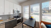 Located at 1606 Abbey Pl in Charlotte, NC, this single-floor unit offers a well-organized layout with a cohesive contemporary design. The kitchen is a standout feature, equipped with stainless steel appliances including a refrigerator, range, microwave, and dishwasher. White gloss upper cabinetry contrasts with darker lower cabinets, while granite countertops and a textured tile backsplash add visual interest. A dining area sits adjacent to the kitchen, positioned beside large windows fitted with horizontal blinds that allow ample natural light and views of the surrounding area.

The living room continues the light-filled theme, with a ceiling fan overhead and a window offering additional outdoor views. Clean white walls and light-toned flooring run throughout the space, creating a bright and airy atmosphere.

The bedroom is a calm retreat featuring high, angled walls that lend a sense of vertical space. Light hardwood-style flooring, neutral walls, and a ceiling fan contribute to a restful environment, with room for décor and furnishings.

The bathroom maintains the unit's clean aesthetic, featuring light tile flooring, granite countertops, and white walls, delivering a functional and polished finish throughout.