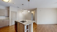 Located at 150 Bear Springs Dr in Winter Springs, Florida, this single-story residence offers a well-designed, open-concept layout with a neutral color palette and thoughtful finishes throughout. The kitchen serves as a central focal point, showcasing a granite-topped island with an undermount sink, pendant lighting, light wood cabinetry, and black stainless appliances including a range, microwave, and refrigerator. Wood-style flooring flows throughout the main living and kitchen areas, creating a warm and cohesive aesthetic. The living area is bright and open, benefiting from a sliding glass door with vertical blinds that invite natural light and provide outdoor access. Bedrooms are carpeted for comfort and each feature ceiling fans and window blinds, with one bedroom offering direct sliding door access. The bathroom is well-appointed with a dual-sink granite vanity, wood-toned cabinetry, a large framed mirror, and a tub-shower combination with clean white tile surround. A generously sized walk-in closet with wire shelving and hanging rods provides ample storage. The overall ambiance is clean, modern, and move-in ready, making this Winter Springs residence a functional and comfortable home.