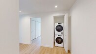 Located on the 9th floor at 351 Marin Blvd in Jersey City, this modern 2-bedroom, 2-bathroom residence offers a well-designed layout with a clean, contemporary aesthetic throughout. Light-toned hardwood flooring flows seamlessly across the entire unit, complementing the crisp white walls and black-framed floor-to-ceiling windows that frame sweeping views of the Jersey City skyline and surrounding neighborhood.

The open-concept kitchen and living area serves as the heart of the home, anchored by a large central island with a dark quartz countertop, integrated sink, and pendant lighting above. The kitchen is outfitted with gray cabinetry, a white subway tile backsplash, stainless steel appliances, and recessed lighting, creating a polished and functional space.

Both bedrooms are generously proportioned, with the spacious primary bedroom offering ample room for furnishings. Each bedroom benefits from large windows that allow abundant natural light and provide elevated city views. Closet space is well integrated throughout.

The two bathrooms are finished in a modern style — one featuring a walk-in glass shower with large-format gray tile surround, and the other with a light wood vanity, white countertop, and a mirrored medicine cabinet above. Each bathroom is clean and efficiently designed, completing this thoughtfully planned urban residence.