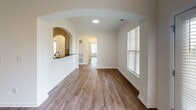 Located at 6440 Mercantile FR in Frederick, MD, this single-floor unit offers a well-designed layout with a cohesive, modern aesthetic throughout. Warm wood-style flooring flows seamlessly across the living areas, bedrooms, and bathrooms, creating a unified and inviting atmosphere.

The living and dining areas are defined by distinctive arched doorways and passageways that add architectural character to the open layout. A pass-through window connects the kitchen to the living area, enhancing the sense of openness. Natural light enters through multiple windows fitted with blinds, offering outdoor views of surrounding greenery.

The kitchen is outfitted with white shaker-style cabinetry, dark granite countertops, a white subway tile backsplash, and stainless steel appliances including a range and over-the-range microwave. The bedrooms are generously sized, each featuring windows with natural light and ceiling fans in select rooms.

The primary bathroom is a standout feature, showcasing an extended double-sink vanity with dark granite countertops, white cabinetry, a large mirror with modern light fixtures, and a separate water closet. A secondary bathroom mirrors the same design aesthetic with a tub-shower combination and granite vanity. Clean white walls and consistent finishes throughout contribute to the space's polished, move-in-ready appeal.