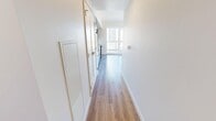 Unit 604 is a well-designed 2-bedroom, 1-bathroom suite located in Calgary, AB, offering a thoughtfully organized single-floor layout that maximizes every square foot. The entry hallway, finished with warm hardwood-style flooring and crisp white walls, leads naturally into the main living areas. The living room is a bright, airy space distinguished by floor-to-ceiling windows and a sliding door to a balcony, flooding the room with natural light and offering open views of the surrounding Calgary cityscape. The kitchen is sleek and functional, featuring dark wood-grain cabinetry extending to the ceiling, light quartz countertops, a white tile backsplash, and a full suite of stainless steel appliances including a refrigerator, dishwasher, range, and over-the-range microwave. The primary bedroom is a comfortable retreat with large corner windows that frame panoramic city views, while a secondary bedroom also benefits from generous window placement and ample natural light. Both bedrooms feature hardwood-style flooring consistent with the rest of the unit. Closet space is provided in the primary bedroom via a dedicated walk-in area with built-in rod storage. The bathroom is clean and modern, appointed with tile flooring, a soaker tub with shower, and a wood-grain vanity with a light countertop.