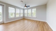 Located at 2307 N Tryon St in Charlotte, NC, this single-story, 2-bedroom, 2-bathroom residence offers 1,030 square feet of thoughtfully arranged living space. The unit features an open-concept kitchen and living room area, providing a versatile layout suited for both everyday living and entertaining.

The living spaces are finished with smooth hardwood-style flooring that runs throughout, contributing to a clean, cohesive aesthetic. Neutral gray walls complement the light tones of the flooring, creating a bright and airy atmosphere. A ceiling fan is centrally positioned, adding both functionality and a finished look to the room.

Large windows with horizontal blinds line the walls, allowing generous natural light to fill the interior while offering views of the surrounding greenery. The abundance of windows enhances the open feel of the space.

The primary bedroom measures 170 square feet, offering comfortable proportions. Both bedrooms are accompanied by dedicated closets, and the two full bathrooms provide convenience for residents and guests alike. The unit's efficient single-floor plan ensures easy accessibility throughout.
