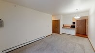 This single-floor residence features three bedrooms and two full bathrooms, offering a functional and well-organized layout. The kitchen is designed for efficiency, featuring hardwood-style flooring, white cabinetry with ample storage, dark stone-finish countertops, and a full suite of black appliances including a range, microwave, refrigerator, and dishwasher. A hallway connects the kitchen to the rest of the home, leading to the carpeted living and sleeping areas. The living and dining area is bright and open, with a pendant light fixture and a sliding glass door that allows natural light to fill the space. Each bedroom is carpeted and finished with neutral tones and wood-trimmed baseboards. Two of the bedrooms feature ceiling fans with light kits and access to closets, including one with built-in shelving and hanging rods. A third bedroom features angled ceiling details, adding a unique architectural element. Both bathrooms include a tub-shower combination. One bathroom is appointed with granite-look countertops, a large vanity mirror, and updated fixtures, while the second offers a clean, simple design with a curved shower rod. Baseboard heating is present throughout the home.