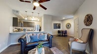 This single-story, 2-bedroom, 1-bathroom residence offers a thoughtfully designed layout that maximizes functionality and comfort. Dark hardwood-style flooring runs throughout, providing a cohesive and elegant foundation for every room.

The open-concept living, dining, and kitchen area forms the heart of the home. The living room is anchored by a fireplace and features a ceiling fan, large windows with plantation shutters, and French doors that invite natural light. The dining area comfortably fits a round table for four, positioned beneath a decorative wall-mounted mirror.

The kitchen is well-equipped with dark cabinetry, stainless steel appliances including a refrigerator and microwave, a white subway tile backsplash, and a generous light-colored countertop peninsula with an undermount sink — ideal for both meal prep and casual dining.

The primary bedroom offers a comfortable footprint with a built-in open closet, access to the hallway, and a window for natural light. The second bedroom also includes natural light and closet space. Both rooms maintain the consistent hardwood-style flooring.

The bathroom is clean and functional, featuring a walk-in shower with large white tile surround, a vanity with light countertops, and modern chrome fixtures. Two hallways connect the spaces efficiently, completing this well-organized and stylish single-floor layout.