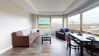 Located in Ann Arbor, MI 48104, this one-bedroom, one-bathroom unit delivers a well-organized layout across a single floor. The living area is a standout feature, anchored by two large wood-framed windows that frame elevated views of the surrounding cityscape, flooding the space with natural light. Hardwood-style flooring runs throughout, lending a clean, cohesive look to every room.

The kitchen is thoughtfully appointed with white shaker-style cabinetry, a subtle mosaic tile backsplash, light countertops, and a full suite of stainless steel appliances including a refrigerator, range, and dishwasher — offering both style and functionality in a compact footprint.

The bedroom is a quiet, well-lit retreat featuring a large window with the same urban backdrop, providing an airy atmosphere and ample natural light. A dedicated study area with a desk and chair makes the room practical for work or study.

Adjacent to the main living space, the dining area benefits from its own window view, creating a pleasant setting for meals. The bathroom is clean and straightforward, featuring a shower-tub combination with tiled surround. Throughout the unit, the neutral color palette and consistent flooring create a unified, modern aesthetic well-suited to urban living in Ann Arbor.