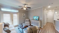 This single-story, 2-bedroom, 2-bathroom home offers a thoughtfully designed layout that balances comfort and functionality. The living room serves as the heart of the space, featuring crown molding, a ceiling fan, wood-look flooring, and a glass-paneled door that welcomes natural light. The room flows seamlessly into a dedicated dining area, highlighted by a pendant light fixture and additional crown molding detailing.

The kitchen is well-equipped with dark espresso cabinetry, granite countertops, stainless steel appliances, and a peninsula that provides additional workspace and casual seating. A washer and dryer are conveniently visible just off the kitchen area. Warm-toned wood-look flooring extends throughout the main living areas, creating a cohesive aesthetic.

Both bedrooms are carpeted and include ceiling fans, offering a cozy retreat. The primary bedroom connects to a private bathroom featuring a granite-topped vanity with dark cabinetry and wood-look flooring. The second full bathroom mirrors this design and includes a tub-shower combination. Neutral gray walls, crown molding, and consistent finishes throughout give the entire home a polished, unified character.