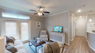 This single-story, 2-bedroom, 2-bathroom home offers a thoughtfully designed layout that balances comfort and functionality. The living room serves as the heart of the space, featuring crown molding, a ceiling fan, wood-look flooring, and a glass-paneled door that welcomes natural light. The room flows seamlessly into a dedicated dining area, highlighted by a pendant light fixture and additional crown molding detailing.

The kitchen is well-equipped with dark espresso cabinetry, granite countertops, stainless steel appliances, and a peninsula that provides additional workspace and casual seating. A washer and dryer are conveniently visible just off the kitchen area. Warm-toned wood-look flooring extends throughout the main living areas, creating a cohesive aesthetic.

Both bedrooms are carpeted and include ceiling fans, offering a cozy retreat. The primary bedroom connects to a private bathroom featuring a granite-topped vanity with dark cabinetry and wood-look flooring. The second full bathroom mirrors this design and includes a tub-shower combination. Neutral gray walls, crown molding, and consistent finishes throughout give the entire home a polished, unified character.