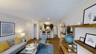 Located at 1100 Audubon Parc Dr in Cary, NC, this single-floor residence offers a well-designed open-concept layout that connects the living, dining, and kitchen areas into one cohesive living space. The living area is inviting and comfortable, featuring warm wood-look hardwood flooring, recessed lighting, and neutral walls that create a bright, airy ambiance throughout. A textured ceiling adds subtle character to the space. The kitchen is efficiently designed with dark espresso cabinetry, white appliances including a refrigerator and range, and a peninsula with bar seating — ideal for casual dining or entertaining. The peninsula serves as a natural divider between the kitchen and living area, maintaining the open feel while providing functional separation. A closet near the entryway offers convenient storage. Recessed and overhead lighting ensure the space is well-lit throughout. The overall palette of whites, warm wood tones, and cool blues creates a calm, welcoming atmosphere. This thoughtfully laid-out residence in Cary's Audubon Parc community combines practical functionality with a modern aesthetic, making it well-suited for comfortable everyday living.