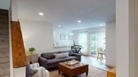 This two-story home offers a thoughtfully designed layout with functional living spaces spread across both levels. The main level centers around an open-concept arrangement where the living room, dining area, and kitchen flow seamlessly into one another. The living room features recessed lighting, wood-look flooring, and connects directly to the dining space, which is brightened by a pendant light and a sliding glass door that opens to an outdoor patio, inviting an abundance of natural light. The galley-style kitchen is well-equipped with white shaker cabinetry, light countertops, stainless steel appliances, and recessed lighting overhead. A cozy seating nook near the staircase provides additional gathering space on this level. Upstairs, the bedrooms are carpeted and feature ceiling fans and multiple windows that allow for ample natural light. The bathroom is finished with a white vanity, framed mirror, and brushed nickel fixtures. A dedicated laundry area with full-size washer and dryer adds everyday convenience. Throughout, the home maintains a clean, neutral palette that creates a bright and welcoming atmosphere.