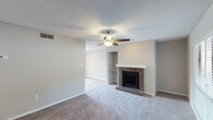 This single-floor residence offers a well-organized layout with distinct living, dining, sleeping, and utility areas. The living room serves as the centerpiece of the home, highlighted by a classic brick fireplace with a white mantle and a ceiling fan overhead. Textured ceilings are consistent throughout, adding a traditional character to the space. Neutral-toned carpet covers the living room and bedrooms, while light wood-look flooring runs through the dining area, kitchen, and bathroom.

The dining area benefits from a sliding glass door fitted with vertical blinds, allowing natural light to fill the space and providing access to the outdoors. The kitchen is well-appointed with white shaker-style cabinetry, granite countertops, a stainless steel sink, a dishwasher, and a range. A large window over the counter brightens the workspace considerably.

The bedrooms are generously sized, each featuring plush carpet, ceiling fans, and windows with blinds that admit natural light. One bedroom includes an adjacent walk-in closet area. The bathrooms feature wood-look tile flooring, a tub-shower combination, and a white vanity, offering a clean and functional design throughout.