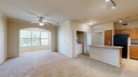 Located in Houston, TX, this 2-bedroom, 1-bathroom residence offers a practical and comfortable single-floor layout. The open-concept living and kitchen area serves as the heart of the home, with the kitchen featuring warm oak cabinetry, stone-look countertops, a peninsula with a double sink, black appliances including an electric range with overhead microwave, and track lighting. Tile flooring runs throughout the kitchen, transitioning to plush carpet in the living and bedroom areas. The living room is accented with crown molding, a ceiling fan, and an arched window that brings in natural light. An in-unit laundry area is conveniently tucked just off the main living space. The primary bedroom offers a generous footprint with a ceiling fan, a dedicated closet, and access to the full bathroom. The second bedroom is similarly carpeted, featuring a ceiling fan and a window with natural light. The full bathroom includes a single vanity with oak cabinetry, a tiled tub-shower combination, tile flooring, and overhead storage. Throughout the home, neutral tones and clean finishes create a cohesive, move-in-ready environment.