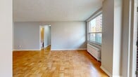 Located at 145 Jameson Avenue in Toronto's vibrant Parkdale neighbourhood, this ground-floor unit offers a practical and well-appointed layout across two bedrooms, one bathroom, a living room, kitchen, and hallway. Throughout the unit, warm parquet flooring in a classic basket-weave pattern adds timeless character to every room. The living room is generously proportioned, featuring a textured ceiling, large windows that draw in natural light, and a radiator unit for efficient heating. Both bedrooms continue the parquet flooring theme and are equipped with radiator heating and sizable windows overlooking the surrounding streetscape, keeping the rooms bright and airy. The kitchen is fitted with white shaker-style cabinetry, brushed nickel hardware, and marble-patterned countertops with a tiled backsplash, offering a clean and functional workspace. The bathroom features a full soaker tub with a tiled surround, a vanity with matching marble-style countertop, and a wall-mounted mirror. Outside, the unit benefits from a private ground-floor entrance with direct access to a well-maintained lawn area. The location provides excellent transit connectivity, with TTC streetcar service running directly along Jameson Avenue.