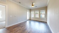 This thoughtfully designed single-story home offers a comfortable and functional layout across one bedroom, one bathroom, and a dedicated laundry area, with two closets providing ample storage. The living room makes a strong first impression with rich hardwood-style flooring, elegant crown molding, recessed lighting, and a ceiling fan. Multiple windows and a glass-paneled door flood the space with natural light while offering views of the surrounding greenery outside.

The kitchen is well-equipped, featuring dark espresso cabinetry, granite-look countertops, a double stainless steel sink, and black appliances including a range, microwave, and refrigerator. The adjacent in-unit laundry area conveniently houses a full-size washer and dryer.

The bedroom is generously proportioned, with soft carpet flooring, a ceiling fan, and multiple windows that bring in abundant natural light. A spacious walk-in closet with built-in wire shelving provides excellent storage solutions.

The bathroom maintains the cohesive design aesthetic with hardwood-style tile flooring, dark cabinetry with a granite-look vanity top, a large mirror, and a full tub-shower combination. Neutral tones throughout the home create a clean, inviting ambiance well-suited for comfortable everyday living.
