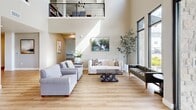 Located at 301 S Calhoun Pl in Star, Idaho, this thoughtfully designed single-floor community facility offers an expansive and welcoming environment across a generously sized footprint. The grand entrance immediately impresses with soaring double-height ceilings, a mezzanine level with sleek metal railings, and light wood flooring that flows throughout the space, creating a cohesive and modern aesthetic.

The open main hall features structural white columns and abundant natural light streaming through large, black-framed windows, offering views of the surrounding Idaho landscape. Multiple seating and gathering areas are arranged throughout, including a comfortable lounge with upholstered sofas and curated artwork, casual dining nooks with stylish pendant and chandelier lighting, and a formal conference-style room with a solid wood table, upholstered chairs, and a wall-mounted display screen.

A well-appointed kitchen serves the facility with wood-toned cabinetry, white quartz countertops, stainless steel appliances including a full-size refrigerator, and ample storage. A private office and a dedicated fitness area with equipment round out the functional spaces. Stone accent columns and warm, neutral tones throughout contribute to an inviting, professional ambiance suited for both community gatherings and day-to-day operations.