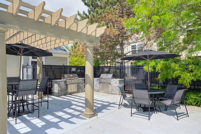 Outdoor grilling area with two grills and table and chairs surrounding. - Hawthorne Commons