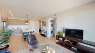 Located at 154 N Berendo St in Los Angeles, this single-floor residence showcases a thoughtfully designed open-concept layout with contemporary finishes throughout. Light wood-style flooring flows through the main living areas, creating a cohesive and airy atmosphere.

The living room serves as the central gathering space, featuring a large sliding glass door that introduces natural light and connects to an outdoor area. The space flows seamlessly into the kitchen, which is outfitted with flat-front taupe cabinetry extending to the ceiling, white quartz countertops, a penny-tile backsplash, and a full suite of stainless steel appliances. A kitchen island provides additional prep and seating space, while modern pendant lighting adds a refined touch.

The bedroom offers a comfortable retreat with plush carpeting, a spacious sliding-door closet, and a large window with neighborhood views. A versatile den or office space features a stylish barn door and provides flexible functionality.

In-unit stacked laundry is conveniently located within the living area. The bathroom includes a combination tub and shower enclosed by a frameless glass door, accented with herringbone tile and matte black fixtures. The overall design is clean, modern, and well-suited for contemporary urban living.