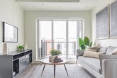 Located at 125 Canon Jackson Drive in Toronto's Mount Dennis neighbourhood, this thoughtfully laid-out two-bedroom, two-bathroom residence offers a clean and contemporary living experience across a single floor. The open-concept layout is anchored by a sleek, modern kitchen outfitted with floor-to-ceiling white cabinetry, a white subway tile backsplash, light quartz countertops, and stainless steel appliances — all set atop light hardwood-style flooring that flows throughout the main living areas. The primary bedroom is a serene retreat featuring a tray ceiling detail, a full-length mirrored sliding closet, and a large glazed sliding door that opens to a private balcony with urban views. The second bedroom maintains the same soft, neutral palette and cozy ambiance. Two well-appointed bathrooms complete the layout: one features a glass-enclosed shower stall with clean white tile finishes and a floating vanity, while the second includes a full soaker tub with white subway tile surround. A connecting hallway ties the space together efficiently. Throughout, crisp white walls, tasteful framed artwork, and an abundance of natural light lend the residence a bright, calm, and modern character.