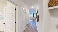 This single-story residence offers a thoughtfully designed layout across three bedrooms and two bathrooms, presenting a cohesive blend of modern finishes and comfortable living spaces. A bright hallway with light wood-look flooring and crisp white walls serves as the central artery connecting the home's key areas.

The open-concept kitchen and living room form the heart of the home. The kitchen features gray shaker-style cabinetry, granite countertops, stainless steel appliances, a center island with seating, and multiple windows that flood the space with natural light. The adjoining living room is generously proportioned, equipped with a ceiling fan, and benefits from large windows dressed with linen-toned blinds and dark drape panels.

The primary bedroom is a comfortable retreat with a ceiling fan, carpeted flooring, and windows offering outdoor views. Two additional bedrooms mirror the same warm, light-filled aesthetic. The two bathrooms are finished with granite-topped vanities, framed mirrors, matte black fixtures, and glass-enclosed showers. Two dedicated closets, featuring wire shelving systems, provide practical storage solutions throughout the home.